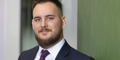 Man standing against a green wall, looking at camera.